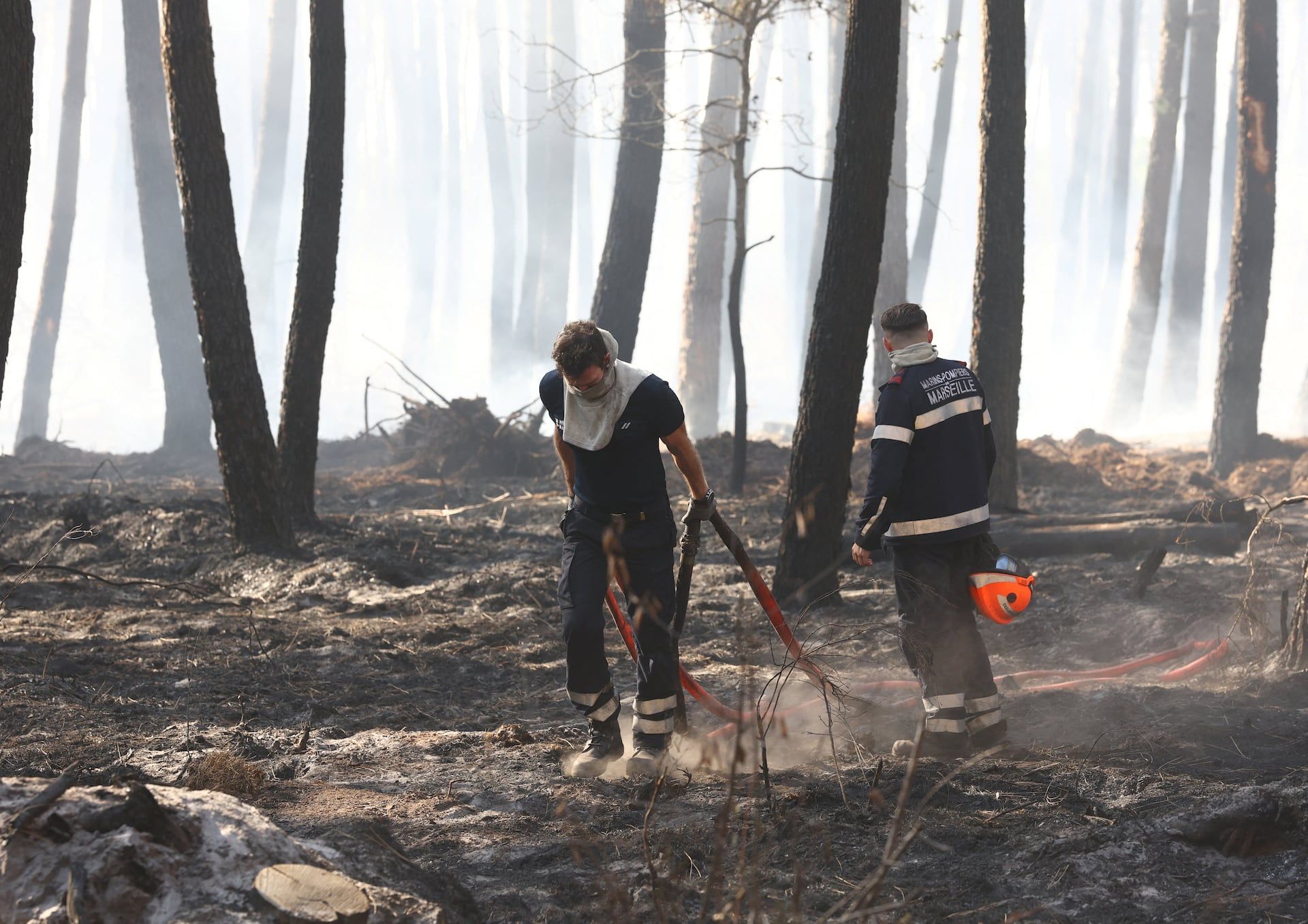 Firefighters walk in a burnt forest amid drought conditions following a heatwave and water shortages across much of France, in Lanton, Gironde, France July 28, 2026. - REUTERS/Yves Herman