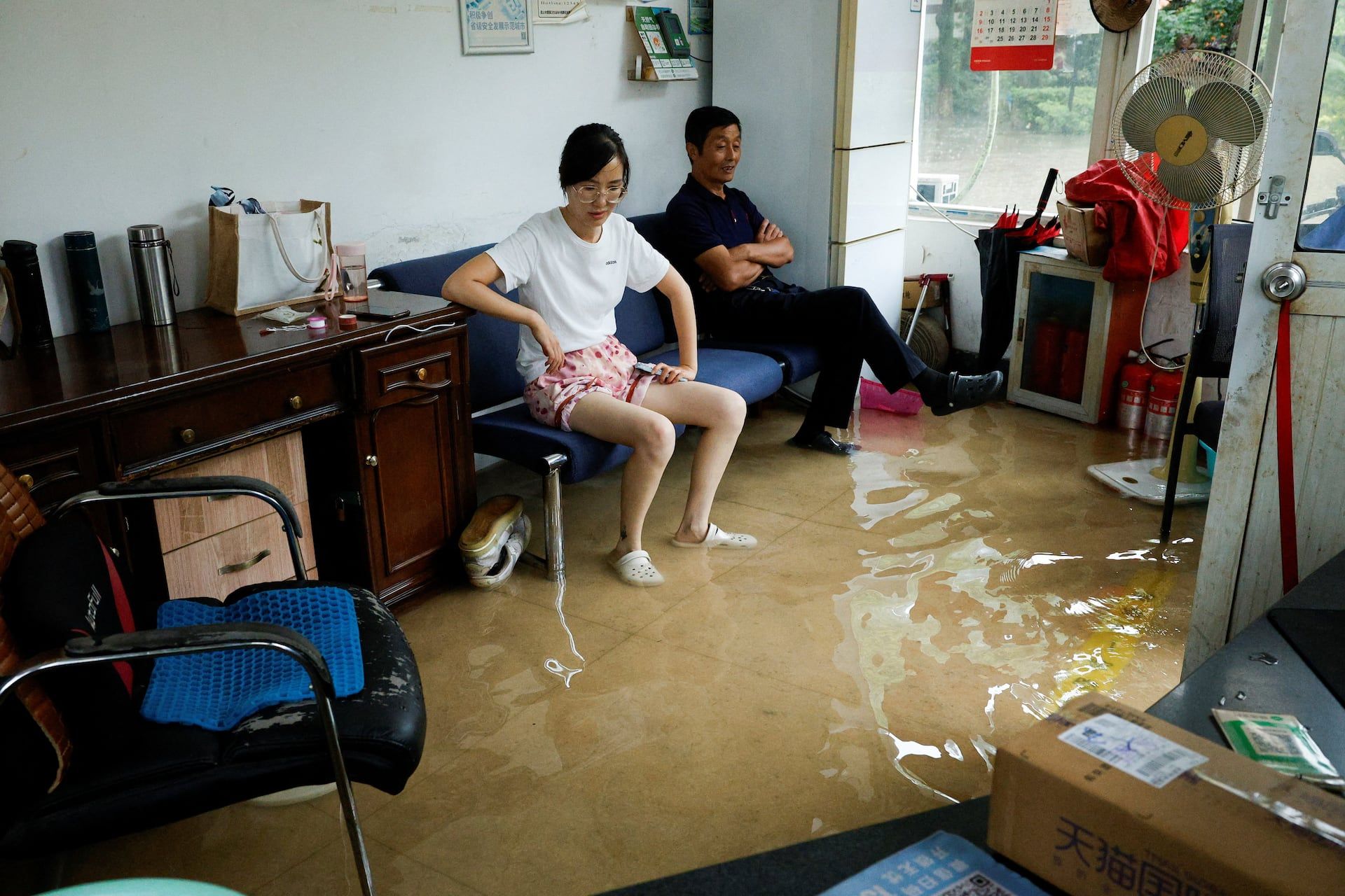 People sit on a sofa in a flooded room after Typhoon Dolphin brought heavy rain to Shanghai, China, August 10, 2026. - REUTERS/Go Nakamura