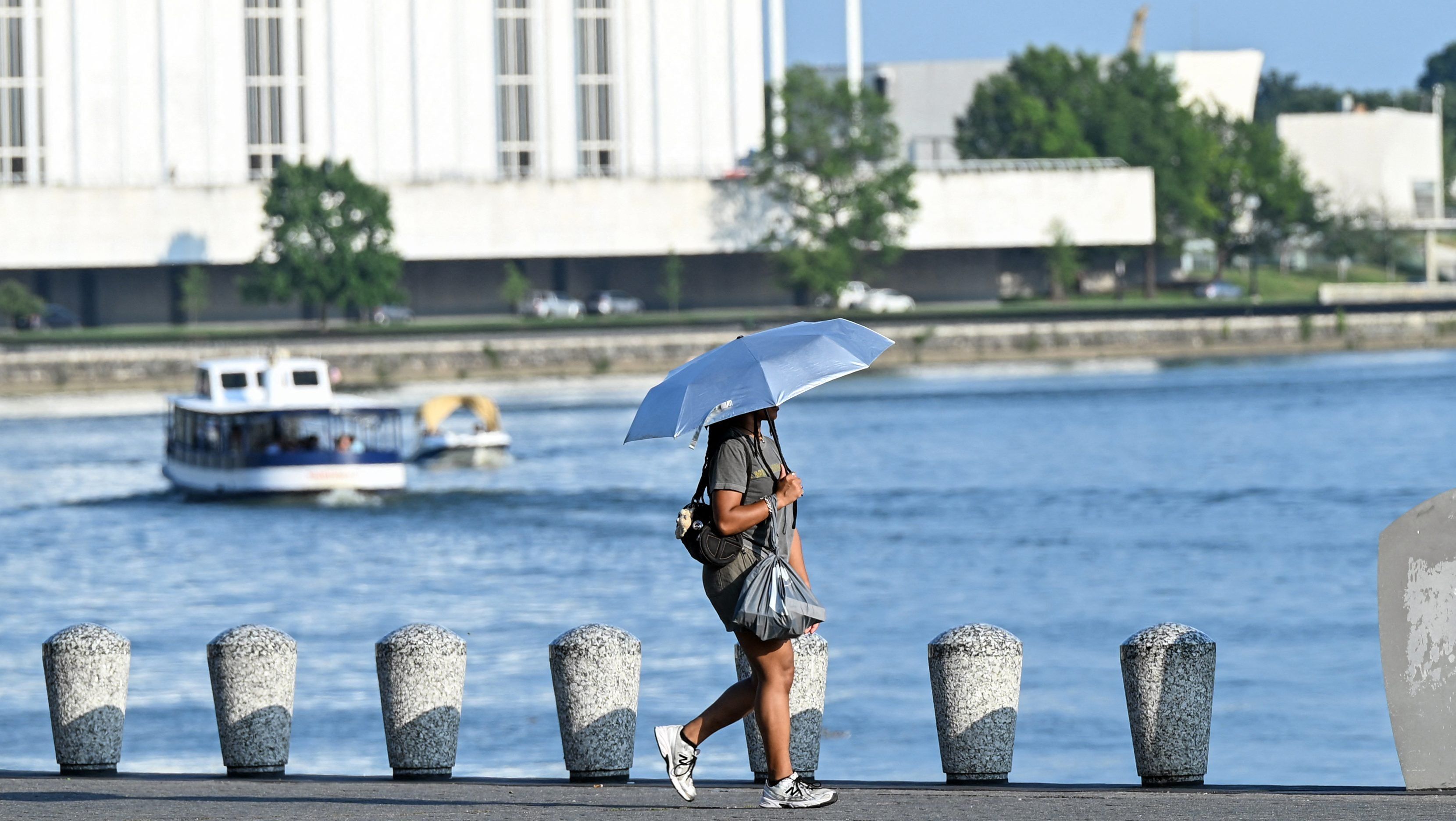 A person uses an umbrella to stay cool while walking along the Potomac River during a heat wave in Washington, D.C., on July 1, 2026. - Alex Wroblewski/AFP via Getty Images
