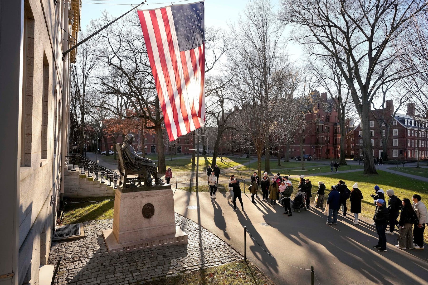 People take photos near a John Harvard statue on the Harvard University campus in Cambridge, Mass. - masslive.com