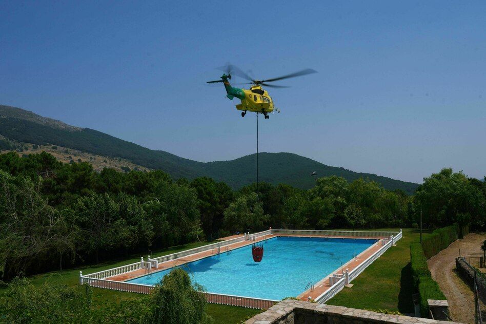 A firefighting helicopter takes water from a pool during a wildfire in Spain’s Ávila province in July. - Manu Fernandez/AP