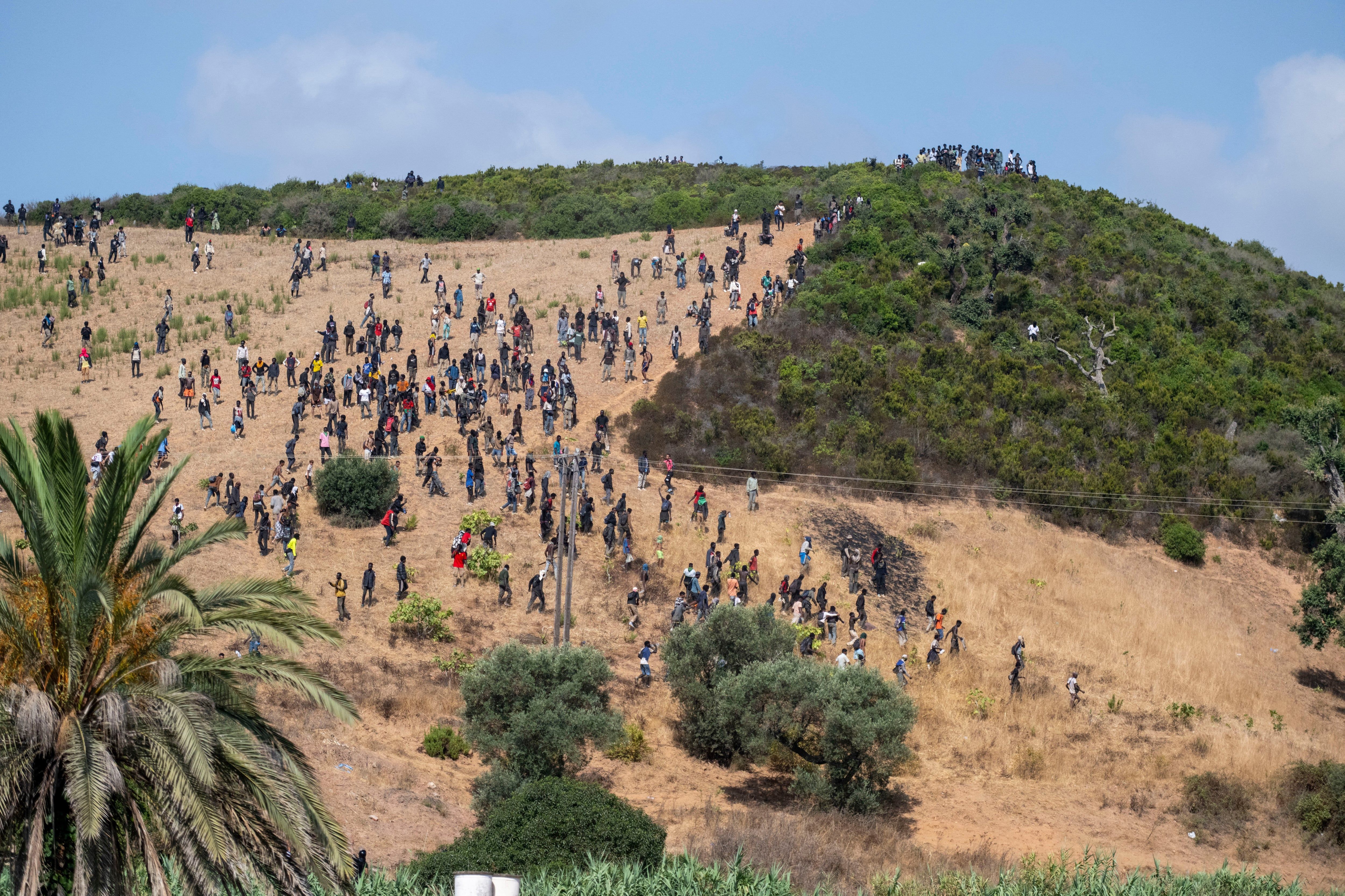 Migrants gather on a hill as they attempt crossing from the border town of Fnideq to the Spanish enclave of Ceuta, Saturday, Aug. 15, 2026. - AP Photo