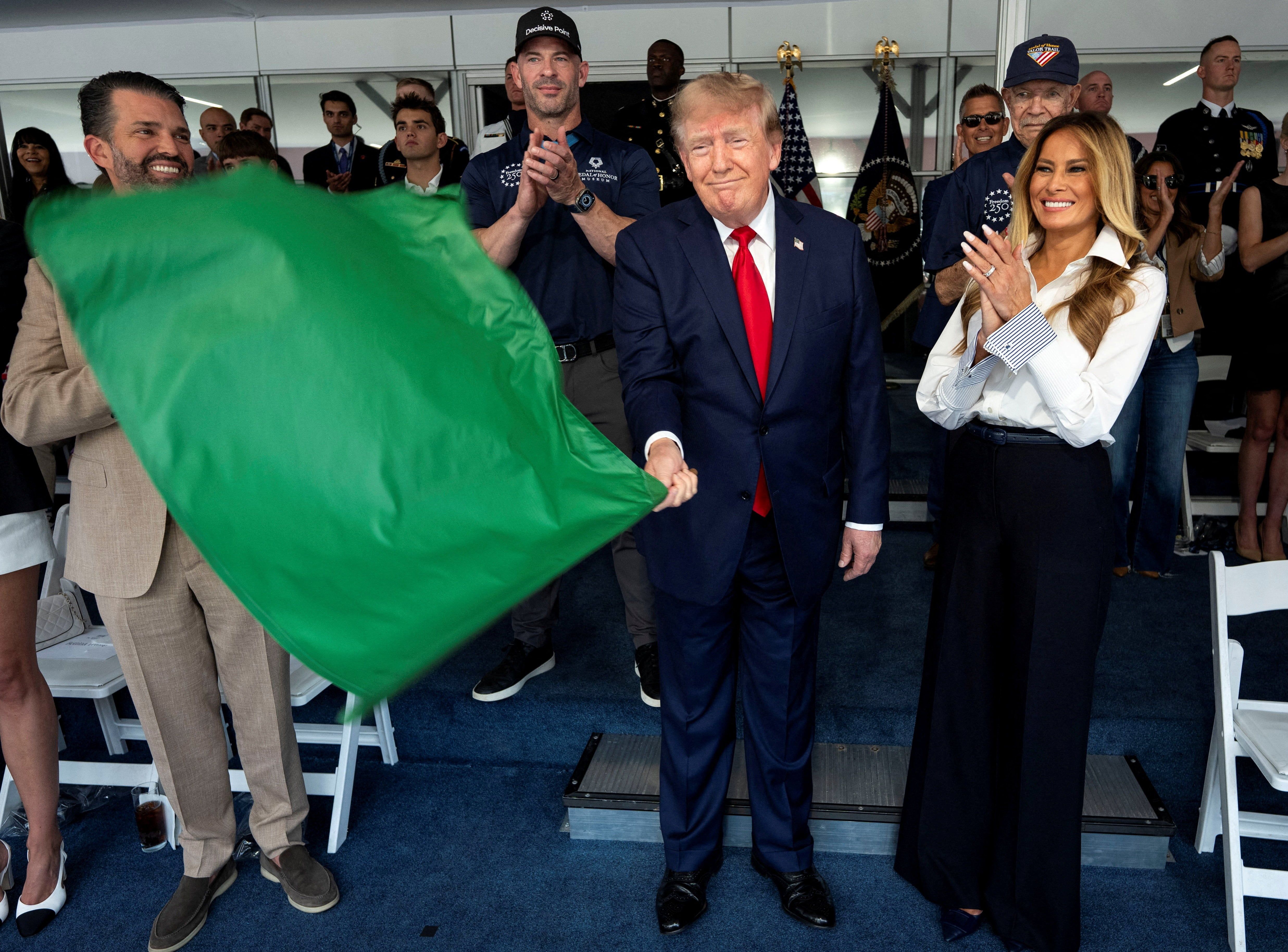 U.S. President Donald Trump waves the green flag to start the Freedom 250 Grand Prix in Washington, D.C., with first lady Melania Trump at his side. - Doug Mills/Pool via Reuters