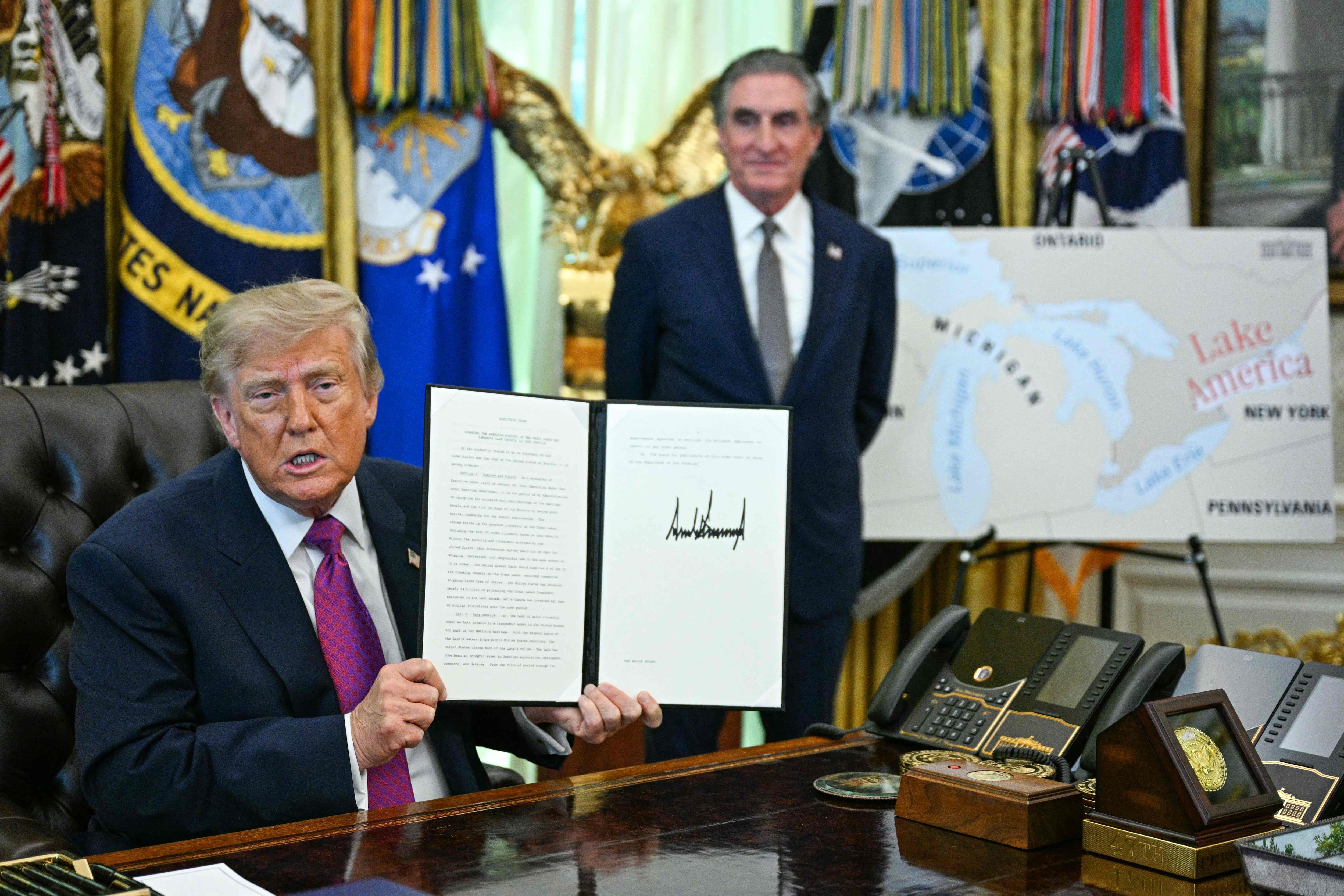 President Donald Trump, with Interior Secretary Doug Burgum, holds up the executive order he signed to rename Lake Ontario. - AFP