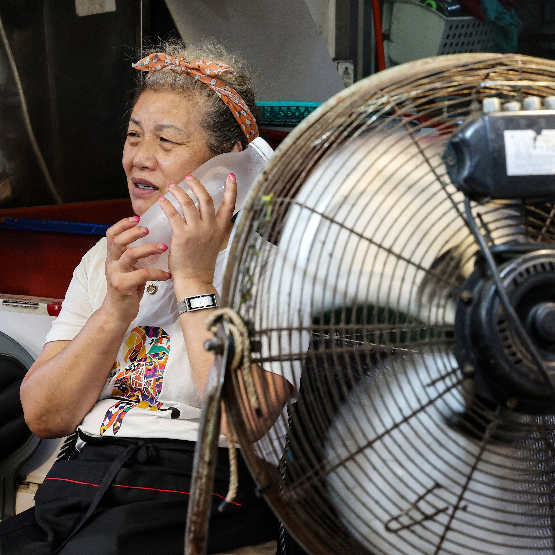 A vendor cooled off with a frozen water bottle in a market in Seoul on Aug. 6. - nytimes.com